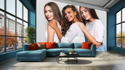 Three beautiful multiethnic women having fun while standing isolated on gray background Wall mural